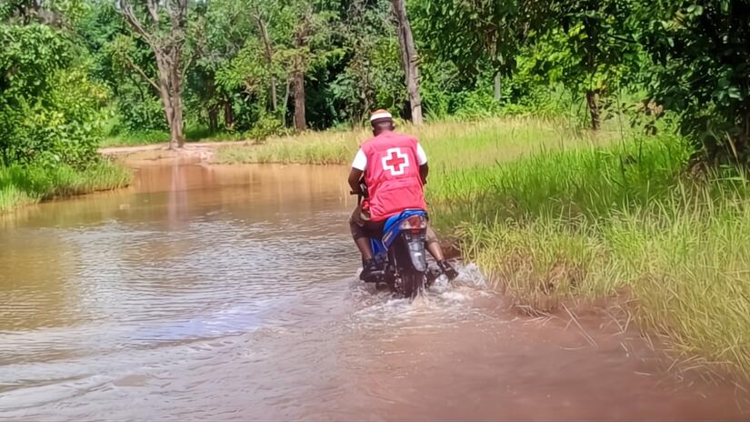 A Mali Red Cross volunteer rides through flood water on his motorbike to reach communities affecting by flooding in late 2024 and make sure children continue to receive their routine immunizations. Photo: Mali Red Cross