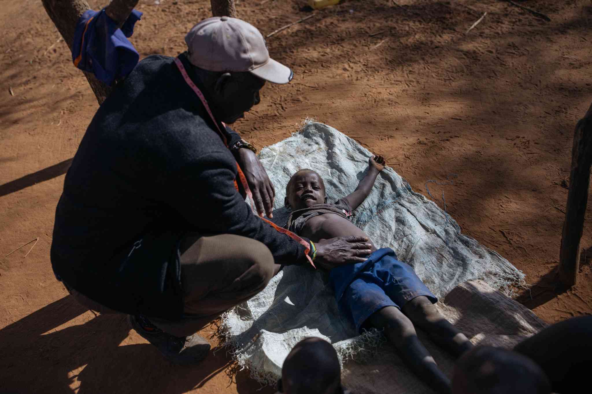 Issac Nyeris, the community mobilizer, checking on Krop Mika, age 6, who recently recovered from Kala-azar, at his home in DungDung, West Pokot.