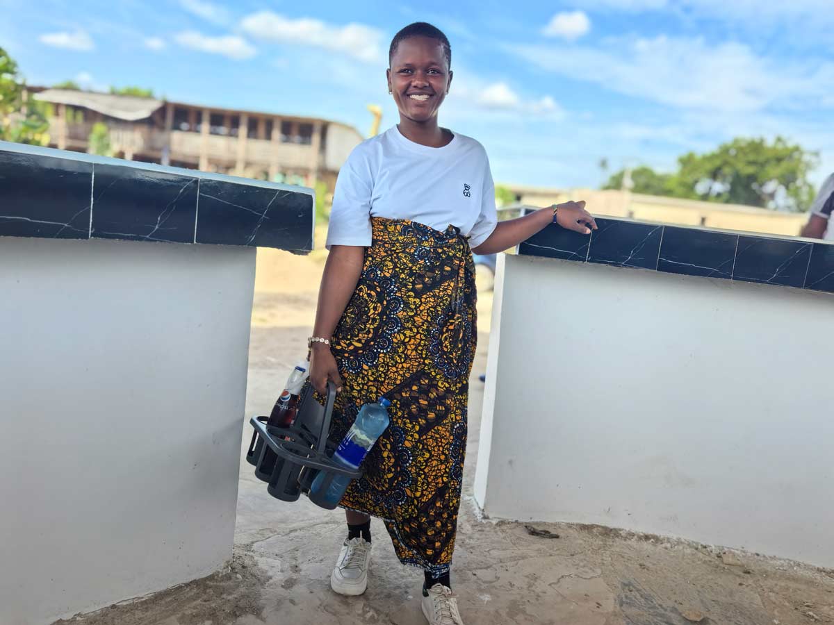 Happiness Nyemo with her serving bucket at the Dar-es-Salaam pub where she earns her living working as a waitress. Credit: Syriacus Buguzi