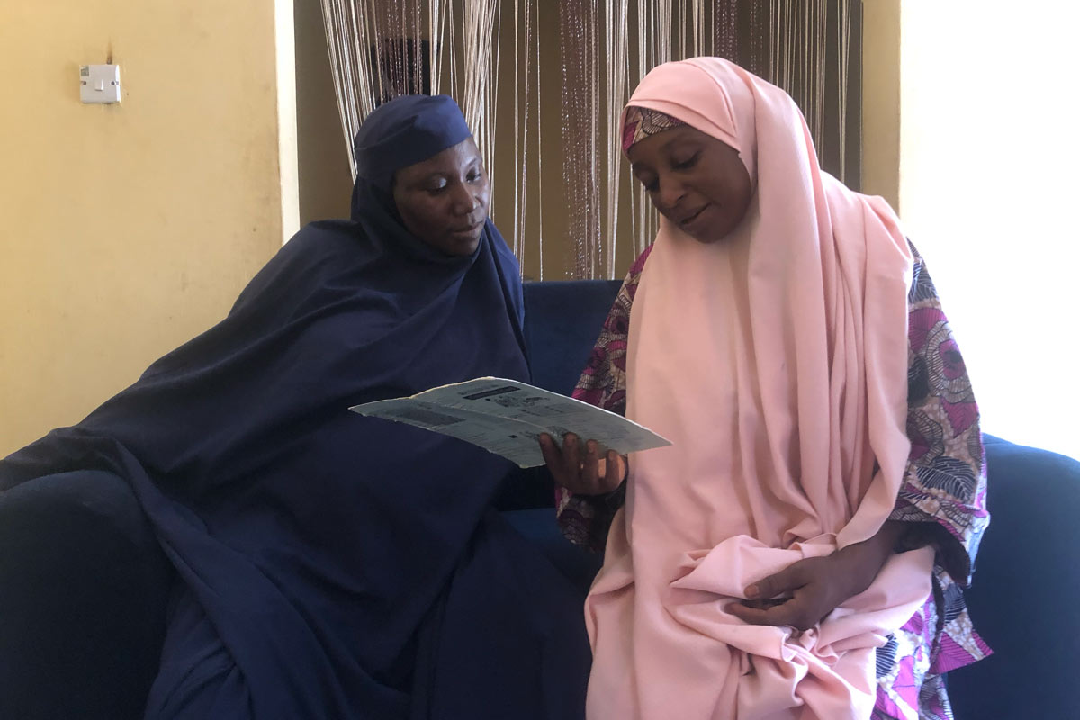Namana Umar (left) and Maryam Umar (right) look through Suleiman Jibrin's immunisation card together. Credit: Ekpali Saint