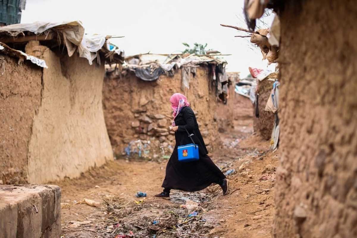 A polio vaccinator trudges through the muddy lanes of a Khyber Pakhtunkhwa slum, determined to reach every child in her door-to-door immunisation campaign. Credit: Emergency Operation Centre, Khyber Pakhtunkhwa