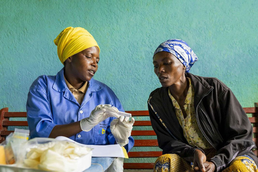 A community health worker speaks with a woman about available health services in Rwanda. Tens of thousands of CHWs deliver essential care, from malaria treatment to cervical cancer prevention. Credit: RBC