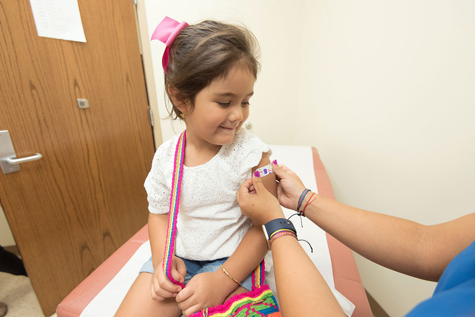 Health care provider was placing a bandage on the injection site of a child. Credit: CDC
