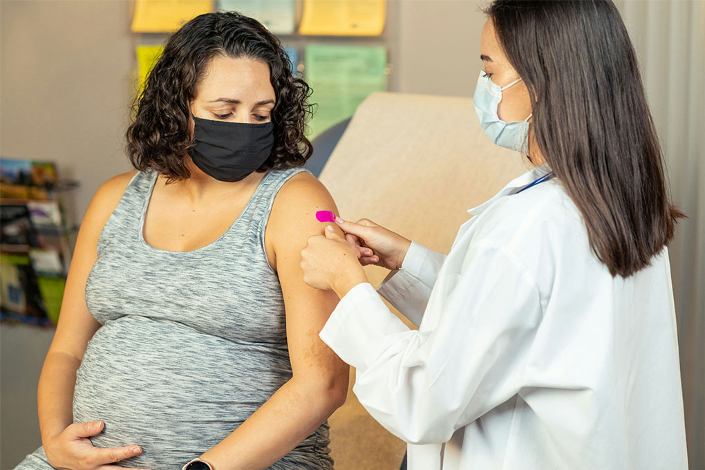 Health care provider places a bandage on the injection site of a pregnant patient. Credit: CDC