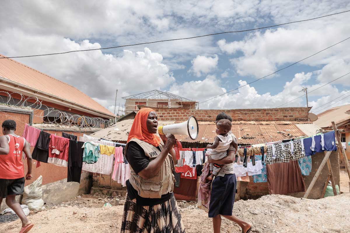 With the help of a megaphone, Rahuma Namata mobilises the community to encourage attendance at a vaccination session. She volunteers as part of the Zero-dose Immunization Program (ZIP) programme. Credit: Gavi/2024/Jjumba Martin