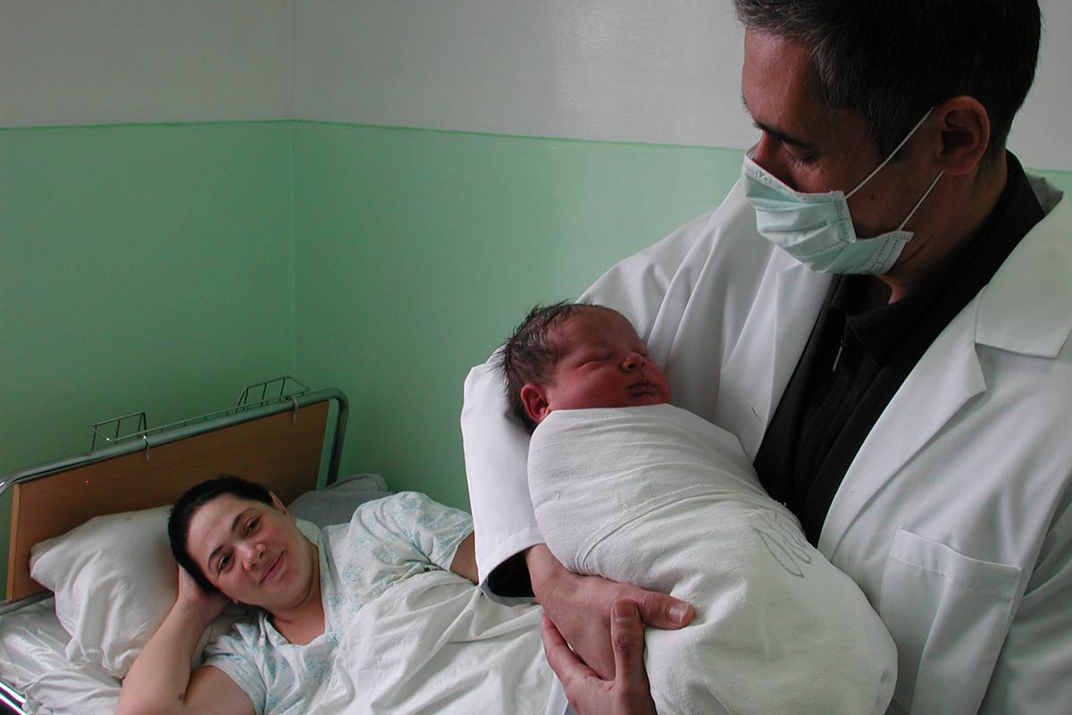 In a Uzbekistan hospital, a doctor holds a baby while the mother looks on from her hospital bed. Credit: Gavi/2013/Thomas Kelly