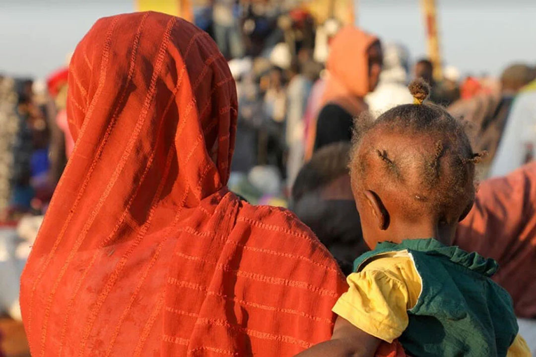 A mother and a child are now refugees at a transit centre in Renk, South Sudan where they arrived with others on 18 December after fleeing escalating violence in Sudan where the health system is collapsing from shortages of medical supplies, a loss of doctors, and destroyed or looted medical facilities. Copyright: Reason Moses Runyanga / UNHCR.