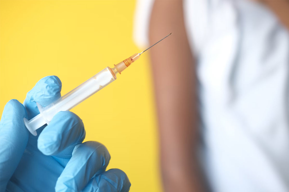 A hand in a blue glove holds a syringe. Towifqu Barbhuiya/ Unsplash
