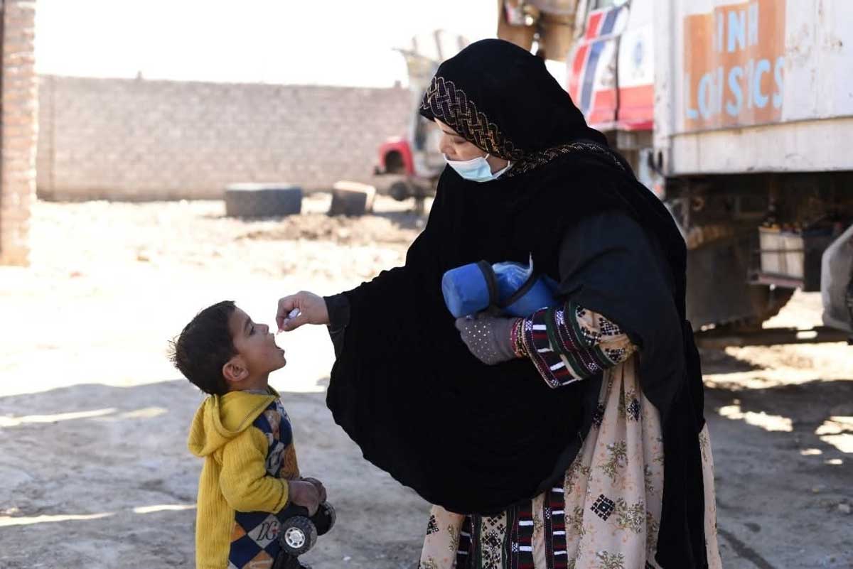 A female health worker administering polio drops to a girl during a door to door immunisation campaign. Credit: Emergency Operation Centre Khyber Pakhtunkhwa. 