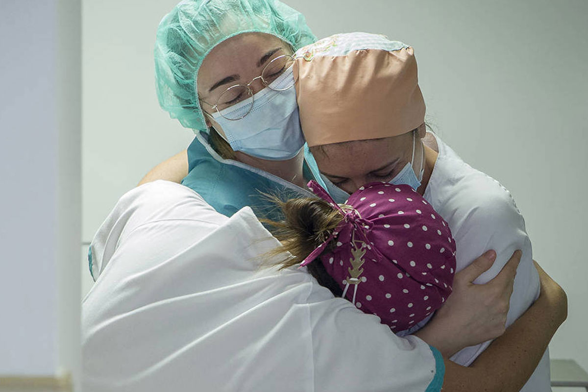 Frontline health workers hug in a hospital corridor. Credit: Europa Press News/ Getty images