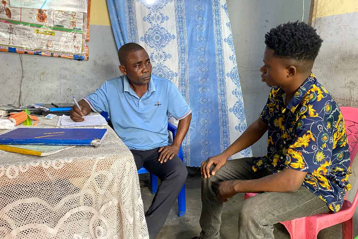 Head nurse Adelon Kweyinatabia speaks with a patient during a consultation at the Kinkenda Community Health Centre, in the Mbinza Météo health zone, Ngaliema municipality, Kinshasa. Credit: Yanne Mbiyavanga