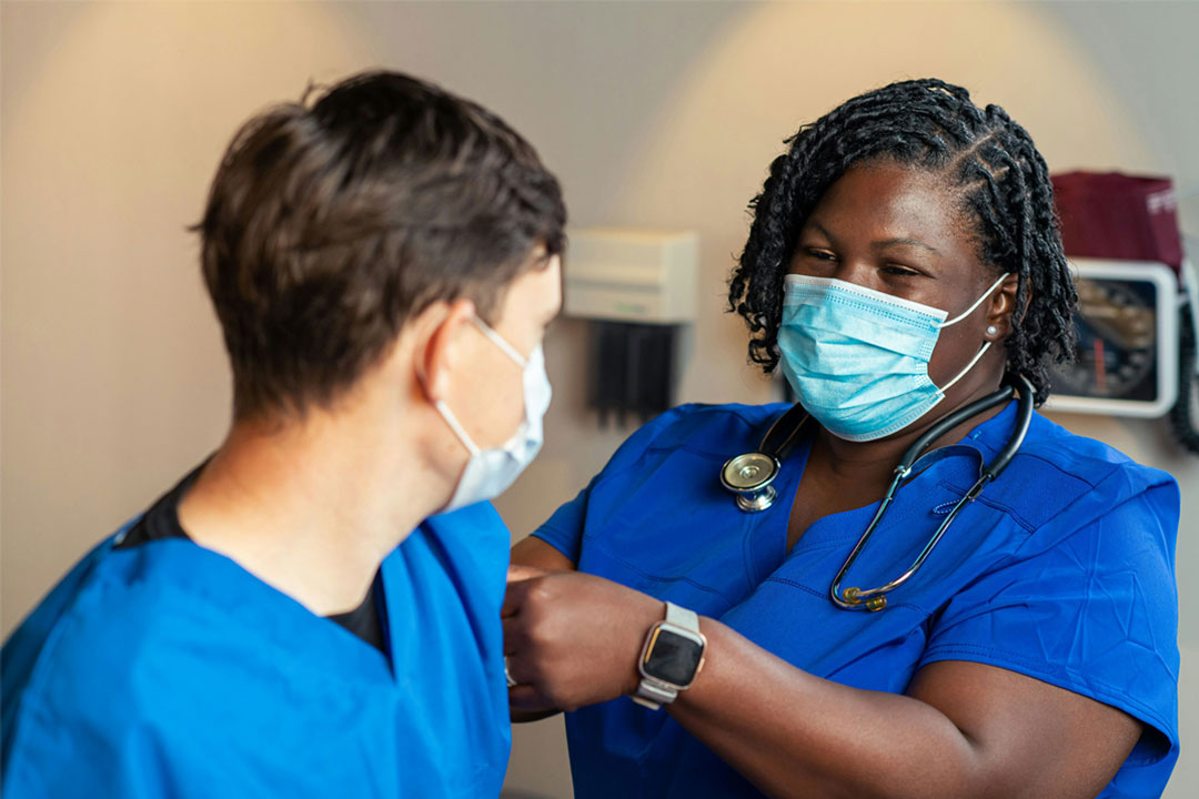A health worker applies a bandage for another health worker who has just received a vaccine. Credit: Centers for Disease Control and Prevention (CDC)