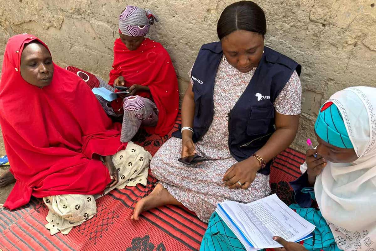 A health worker and caregivers review immunization records. Credit: Nigeria Learning Hub, AFENET