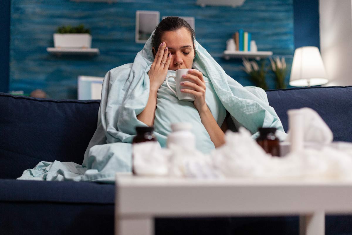 Sick woman sitting at home in blanket with hot tea. Credit: DC Studio/Freepik