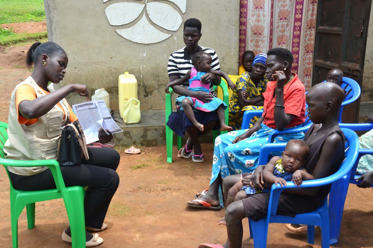 Yesco Maureen, a Community Health Extension Worker (CHEW) for Alivu parish in Maracha district guiding memebers of a family on the dates for malaria vaccination during home visits. Credit: John Musenze
