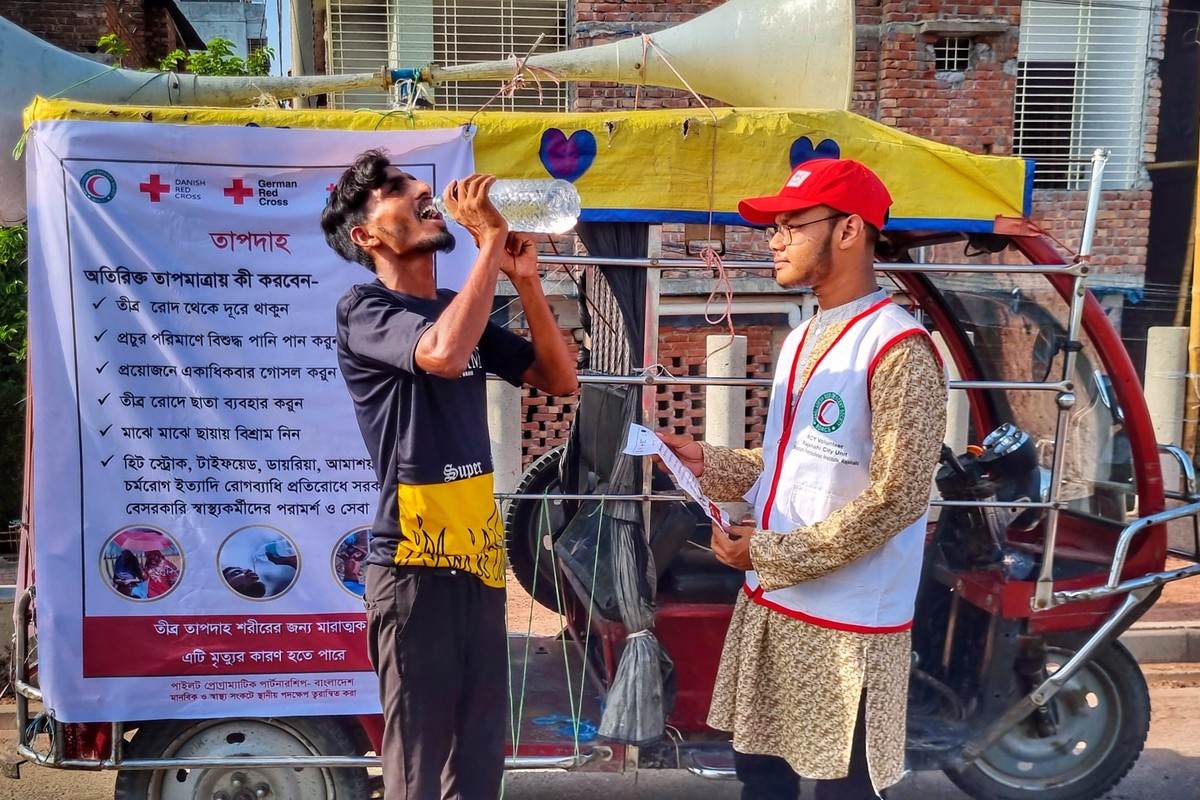 A Bangladesh Red Crescent volunteer distributing drinking water and offering advice to a man in Dhaka on how to stay safe during the latest extreme heat to affect the country, June 2023. Image by BDRCS / Climate Centre via Flickr (CC BY-NC 2.0).
