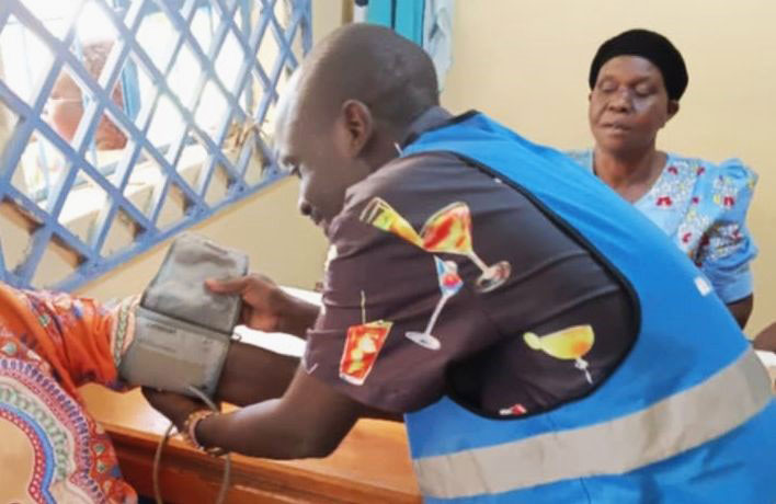 Kelvin Omega taking blood pressure readings from patients at Iduku dispensary. Photo by Pius Sawa