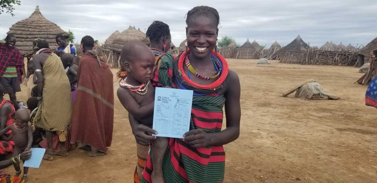 A mother in South Sudan displaying her child’s health card after receiving vaccination.
