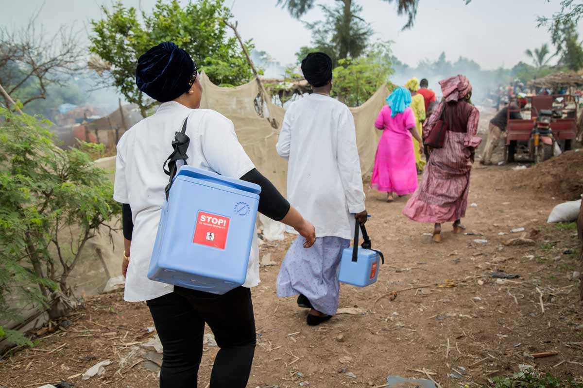 Health workers carrying vaccines in cold boxes. Credit: Gavi/2018/Simon Davis