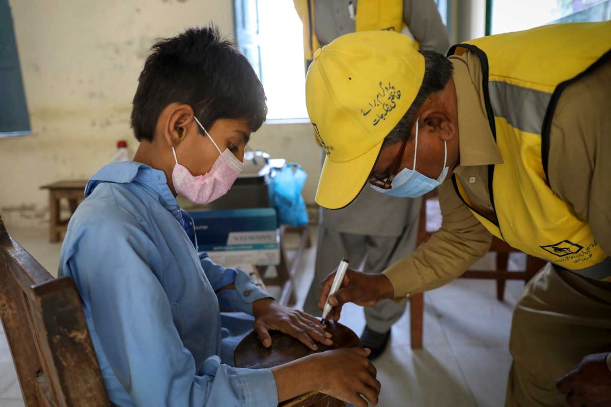 A health worker marks the little finger of a boy after receiving the  vaccine against measles and rubella. Credit: Gavi/2021/Asad Zaidi