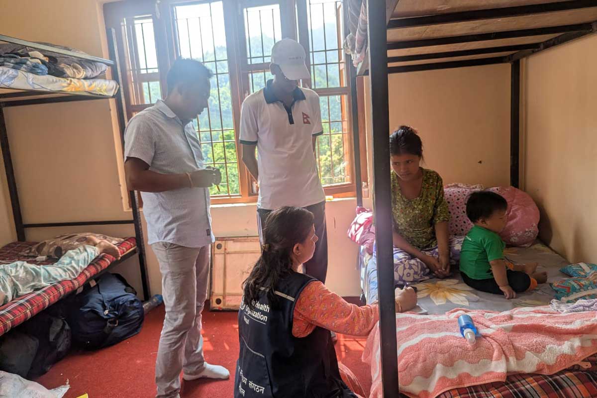A health worker checks the health status of a child staying in a camp at Nilkantha Secondary School in Rasuwa after showing measles-like symptoms. Credit: Public Health Office Rasuwa