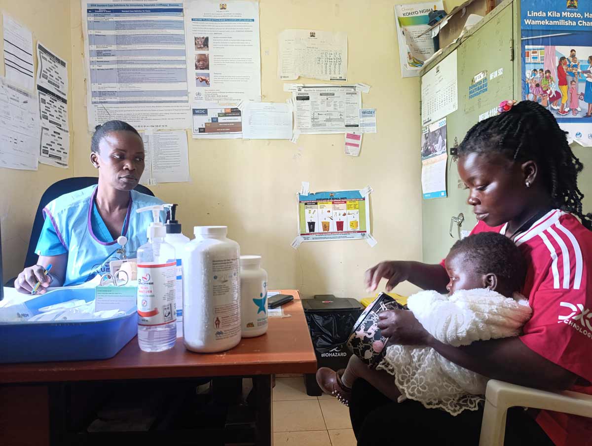 Nurse Presence Omog attends to two year old Maryanne Akinyi during a routine PNC clinic with her mother, Immaculate Achieng. Credit: Angeline Anyango.