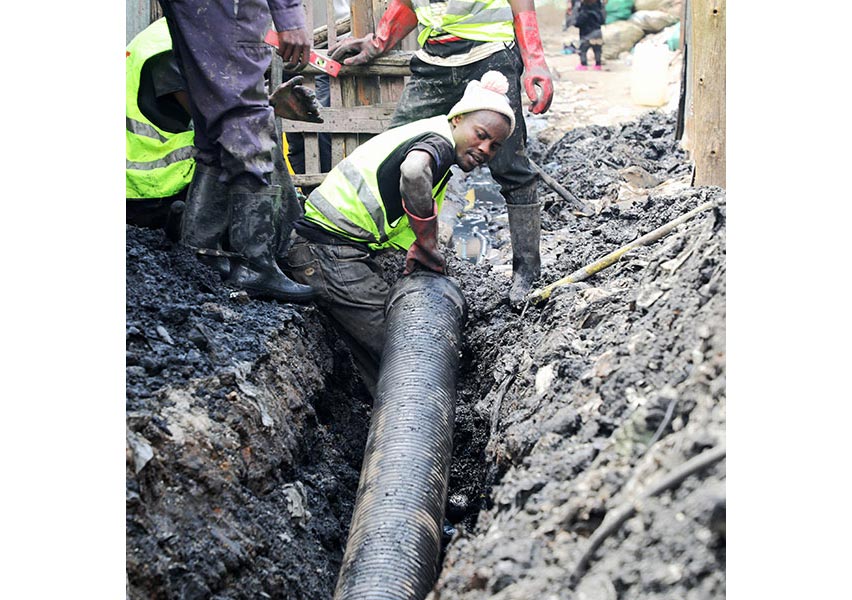 In an informal settlement in Nairobi, Kenya, people install a simplified sewer. These smaller pipes will connect residents of dense communities to the larger main sewer lines. CREDIT: COURTESY OF AKIBA MASHINANI TRUST