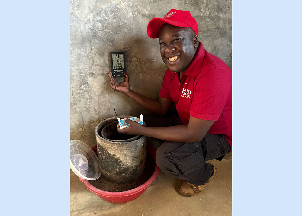 Ahmed Lugelo checks the temperature inside an enclosed clay device, known as a zeepot, that keeps vaccines at safe temperatures. Courtesy Rabies Free Africa