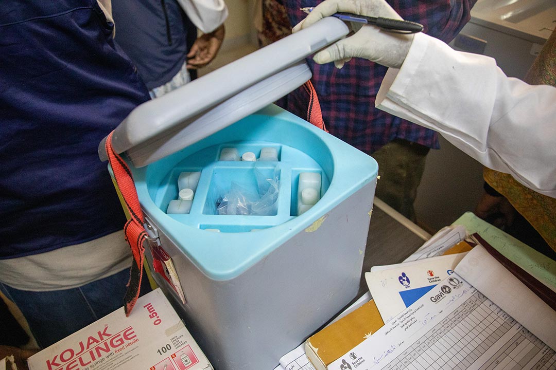 A nurse opens a cold chain vaccine storage box in a health facility. Save the Children/2026/Simon Edmunds