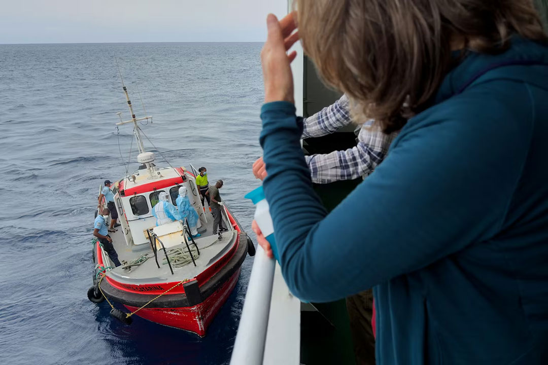 Passengers on the the hantavirus-stricken cruise ship MV Hondius watch epidemiologists board the boat in Praia, Cape Verde, on May 6, 2026. AP Photo/Uncredited