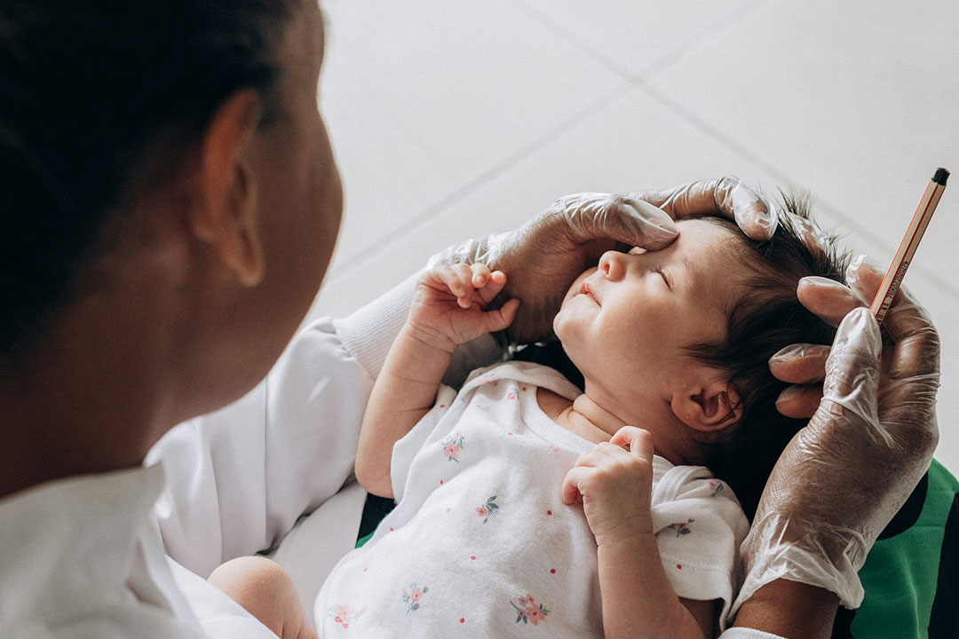 Health worker holding a newborn in her lap. Photo by Jonathan Borba on Unsplash