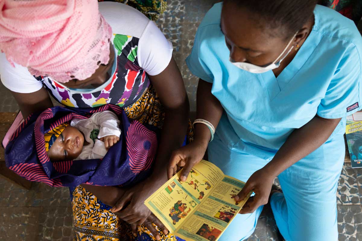A nurse shares educational materials with mother to protect her family from malaria. Copyright: Raw Pixel (CC BY-SA 4.0)