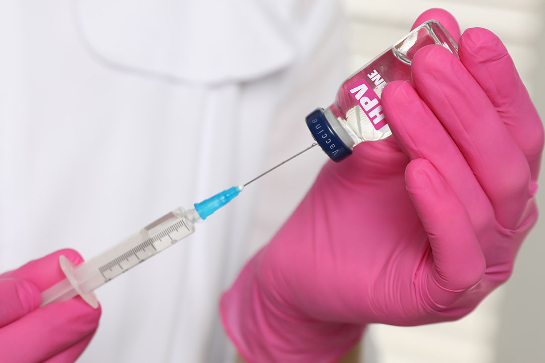 HPV vaccine. Healthcare worker with vial and syringe, closeup.