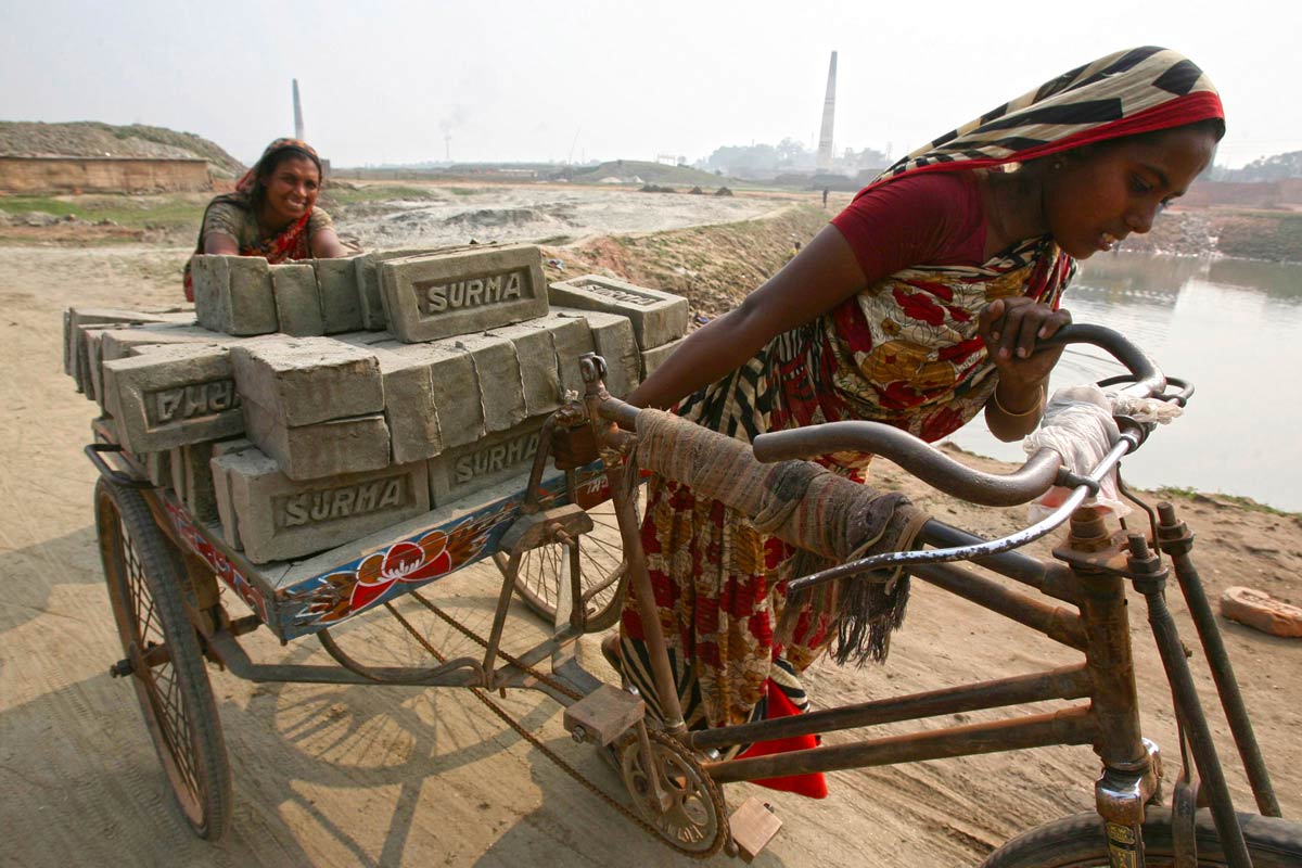 Climate refugees Rabeya Khatoon, right, and Moriom Bibi, who lost their homes to cyclone Aila, work at a brick field on the outskirts of Dhaka in the heat, 2009. Image by AP Photo/Pavel Rahman.