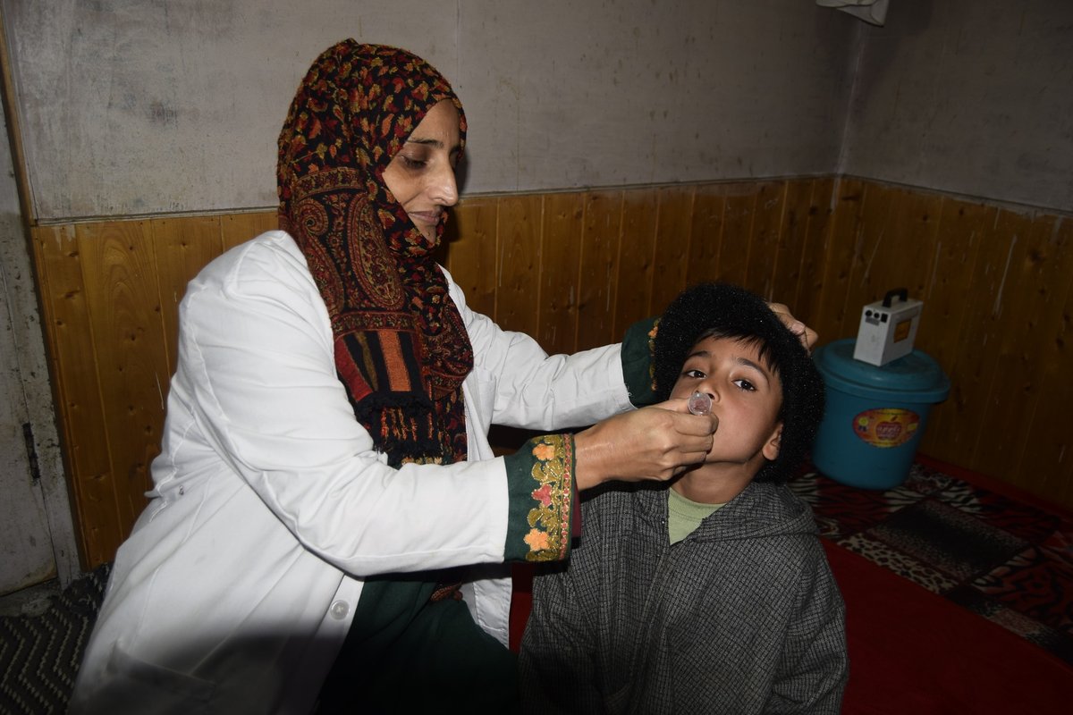 A paramedic administers an oral vaccine to a child in Keran .