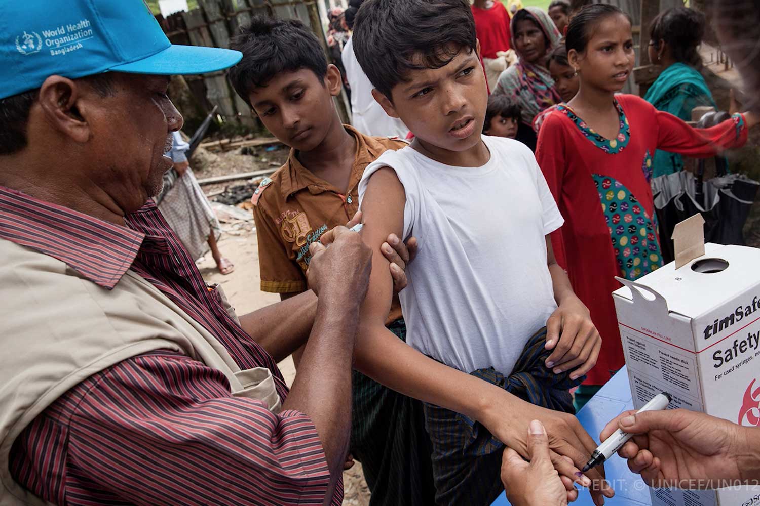 A male health worker administering a vaccine to a boy
