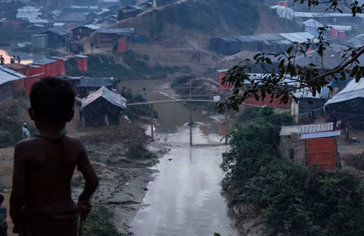 A boy standing overlooking a refugee camp